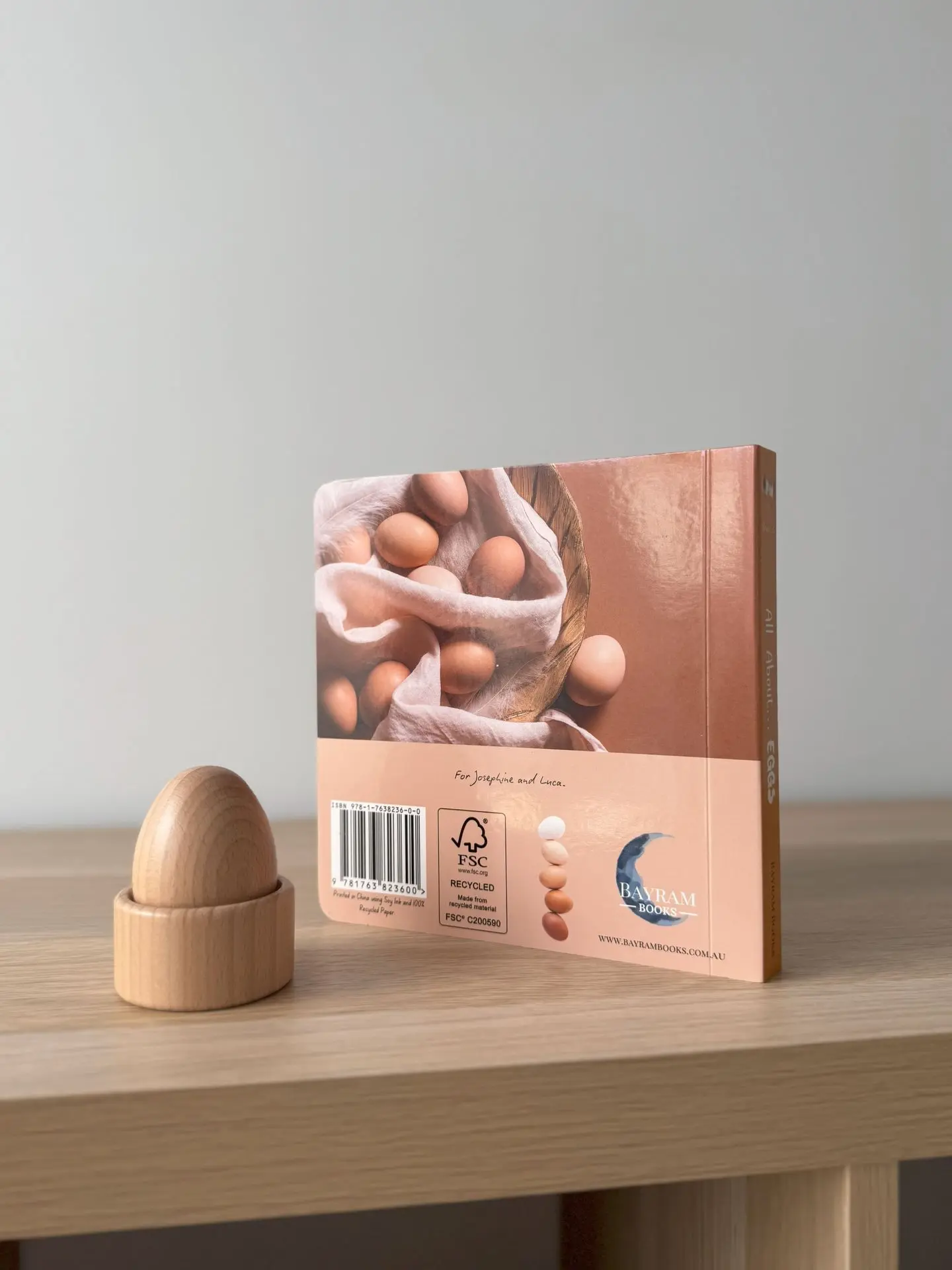 All about eggs book placed on a shelf with a toy egg next to it.